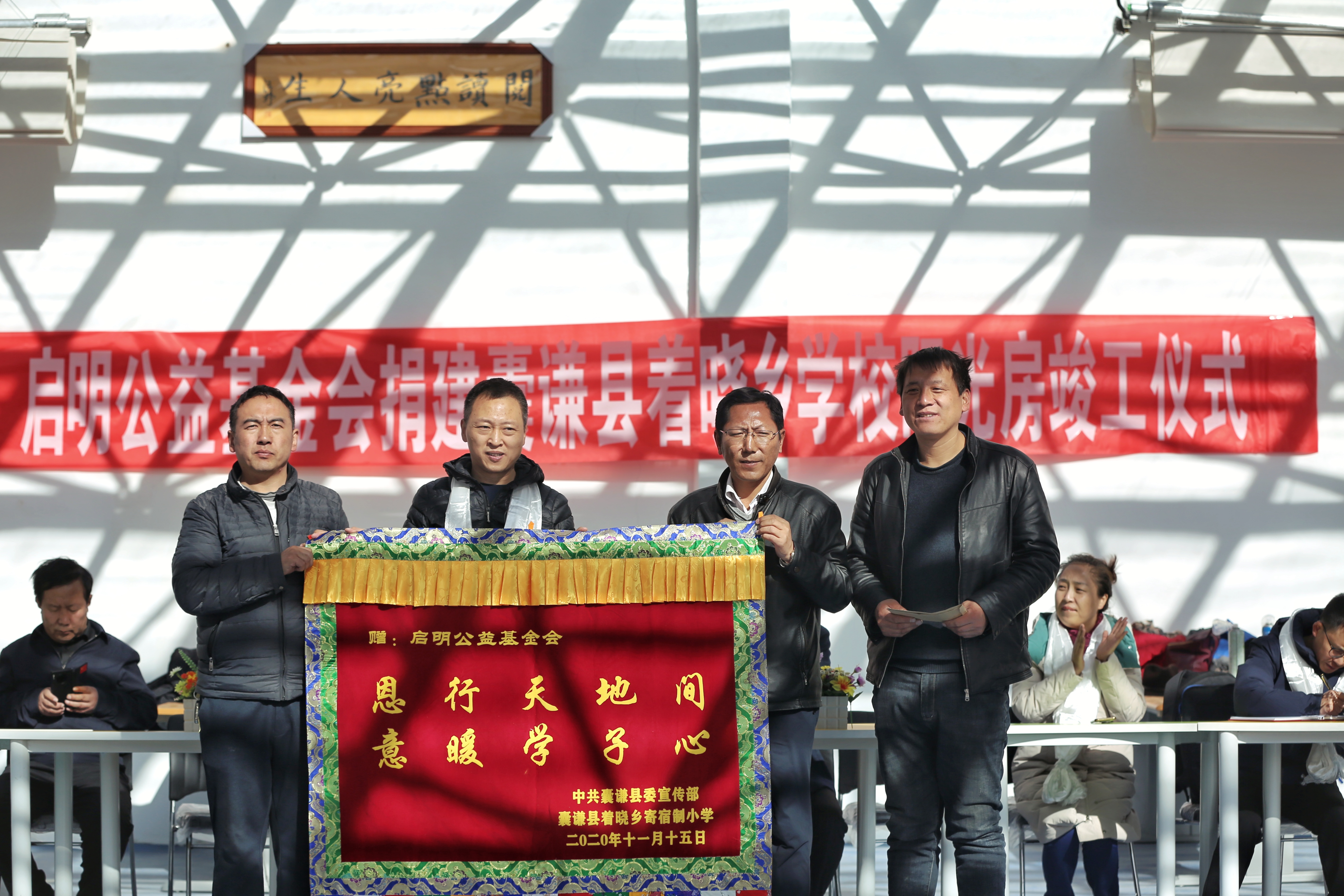 縣委宣傳部部長索南扎西和著曉鄉寄宿學校副校長張廣偉為啟明公益基金會送上錦旗